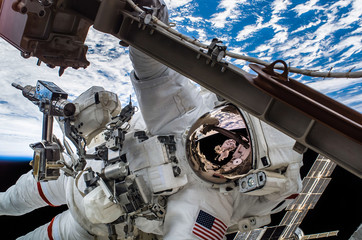 Wall Mural - astronaut float in the space in weightlessness working on the spaceship near to planet earth Elements of this image furnished by NASA