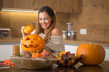 Beautiful young woman smiling and making pumpkin halloween decoration