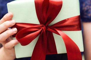 Hand Holding Gift In Package With red Ribbon, holidays concept 