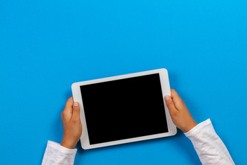 Wall Mural - Kid hand holding white tablet computer on light blue background