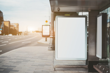 City bus stop on with an empty banner mock-up; template of advertising banners in the stop of public transport; blank information placeholder mockup in urban settings on the pavement near a big road