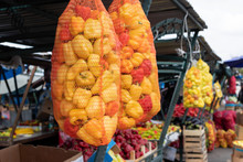 Sweet Yellow And Red Paprika Hanging In A Mesh Bag On A Market C