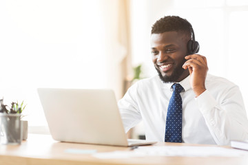 Happy consultant with headset looking at laptop
