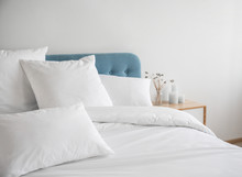 White pillows and duvet on the blue bed. White pillows, duvet and duvet case on a blue bed. White bed linen on a blue sofa. Bedroom with bed and bedding. Front view