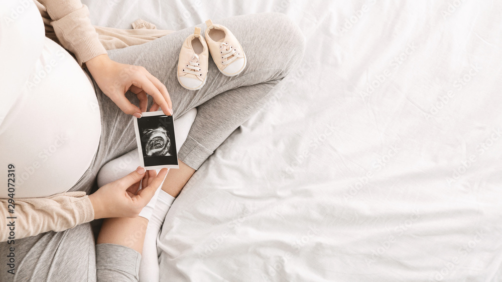 Pregnant woman enjoying future motherhood with first ultrasound photo - obrazy, fototapety, plakaty 