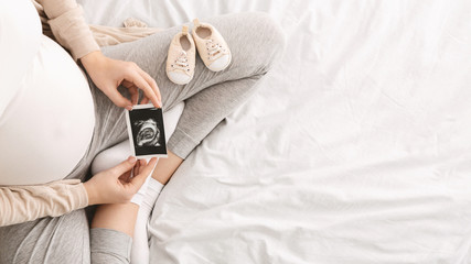 pregnant woman enjoying future motherhood with first ultrasound photo