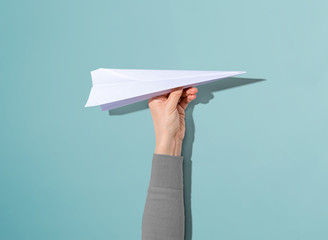 Person holding a paper airplane with hard shadow