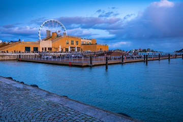 Wall Mural - Helsinki. Finland. Ferris wheel on the background of houses. Harbor capital of Finland. Panorama of Helsinki on a cloudy day. Ferris wheel against the clouds. Trip to Helsinki.