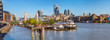 Panorama view of the Tower bridge over Thames river on a sunny day with wharf and boats. City Financial district skyscrapers and Tower of London in the background.
