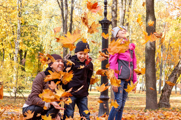 happy family playing with fallen leaves in autumn park