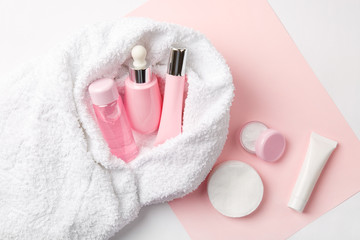 Wall Mural - Face care products (tonic or lotion, serum, cream, micellar water, cotton pads) covered in towel on pink, powder background. Freshness and face care. Skin cleansing and anti-age care. Female cosmetics