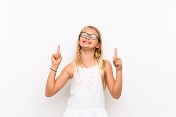 Little girl over isolated white wall pointing up