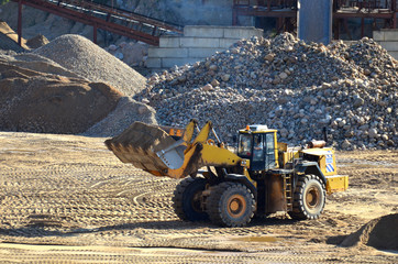 Canvas Print - Large heavy front-end loader or all-wheel bulldozer for mechanization of loading, digging and excavation operations in open quarry. Crusher plant with belt conveyor, crushing process, grinding stone