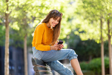 Happy Woman Looking At Mobile Phone In Park