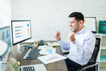 Wall Mural - Hispanic Businessman Enjoying Successful Data At Desk