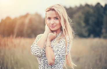 Close Up Portrait of beauty girl with fluttering white hair enjoying nature outdoors, on a field. Flying blonde hair on the wind. Breeze playing with girl's hair. Beautiful young woman face closeup.