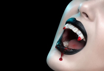 Fototapeta vampire teeth with dripping blood, woman's black bloody lips close-up. vampire girl fangs. fashion halloween art design. close up of female vampire mouth, teeth. isolated on black background