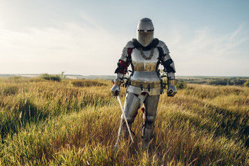 Knight in armor and helmet holds sword