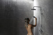 © Alena Ozerova - Woman taking shower in dark modern bathroom interior
