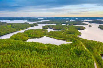 Canvas Print - Aerial view of road between green summer forest, islands and blue lake in Finland.