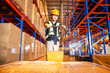 Warehouse worker unloading goods pallet with hand pallet truck at storage warehouse