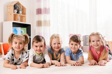 playful little children lying on carpet indoors