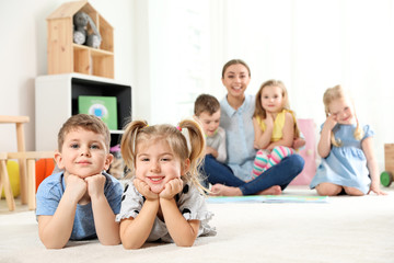 Poster - Playful little children lying on floor indoors. Space for text