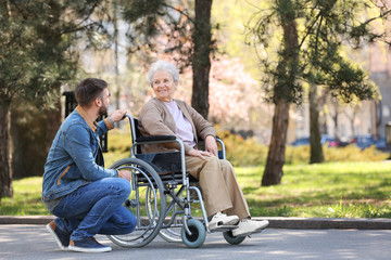 Canvas Print - Senior woman in wheelchair with young man at park