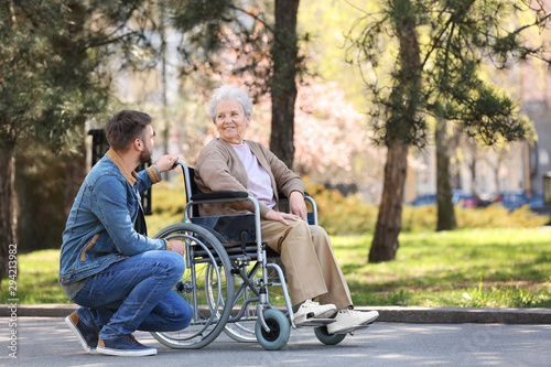 Fotografía Senior woman in wheelchair with young man at park