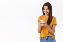 Cheerful, Friendly-looking Feminine Woman In Yellow T-shirt Messaging, Smiling Happy And Delighted, Browsing Internet Using Smartphone, Shopping Black Friday Online, Place Order, White Background