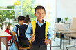 © New Africa - African-American boy wearing school uniform with backpack in classroom