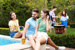 © New Africa - Happy friends with drinks at barbecue party near swimming pool outdoors