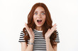 Surprised enthusiastic cute, ginger girl in striped t-shirt hearing excellent news, open mouth excited and impressed, gasping thrilled, stare camera at breathtaking copy space, white background