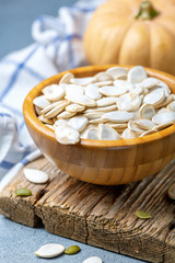 Wall Mural - Unpeeled pumpkin seeds in a wooden bowl.