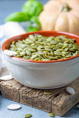 Wall Mural - Raw pumpkin seeds in a ceramic bowl.