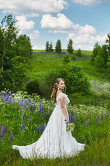 Canvas Print - Romantic beautiful bride on sunny summer day outdoors. Young blonde woman in a beautiful wedding dress is posing in blooming field. Concept of wedding photoshoot in rustic style