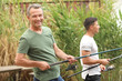 © Pixel-Shot - Young man and his father fishing on river