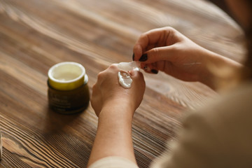 Close-up woman applying cream on hands. Natural light. Texture of cream. Healthcare cosmetics concept.