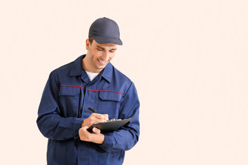 Wall Mural - Male car mechanic with clipboard on color background