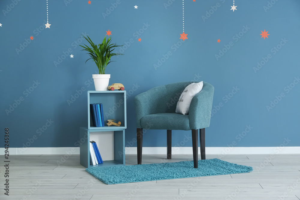 Shelf unit and armchair near color wall