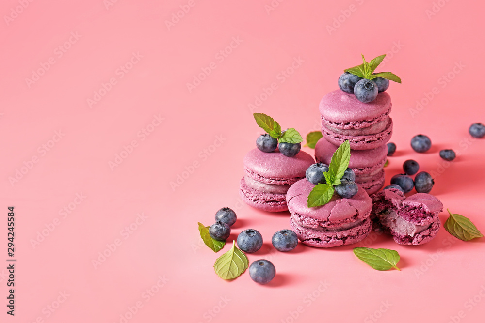 Tasty blueberry macarons with mint on color background