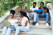 © F8  \ Suport Ukraine - Happy african students sitting on stairs in park