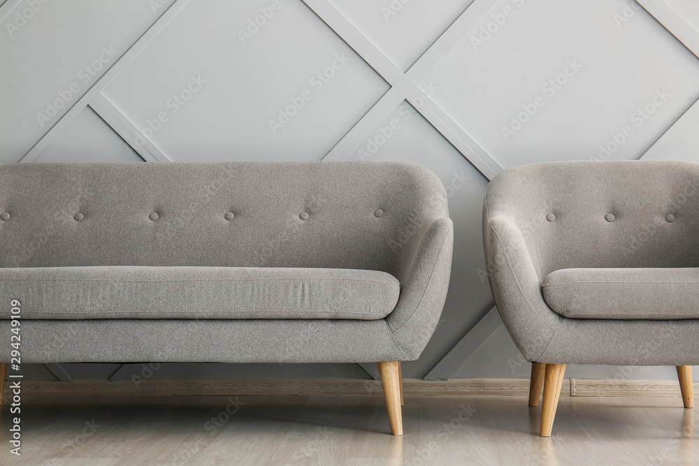 Modern sofa and armchair near light wall