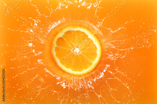 Fotografía Falling of orange piece into juice, top view