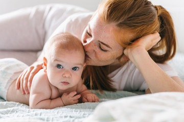 mom hugs with her newborn baby in bed. four month old baby. baby care, tenderness, motherhood