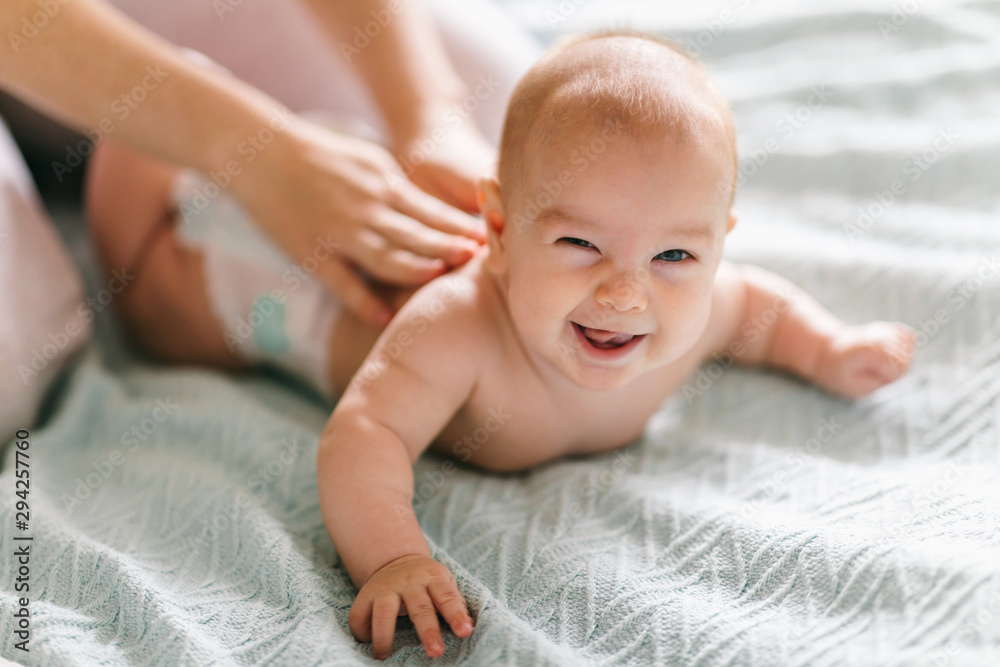 Massage for the baby. Four month old baby smiling doing gymnastics - obrazy, fototapety, plakaty 