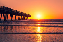 Sun Rising Over Horizon And Pier, Beach Illuminated With Sunlight, Beautiful Sunrise In Florida. Jacksonville Florida, USA.