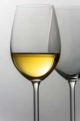 Close up of glass of white wine, against grey background.