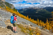 © aquamarine4 - Woman on a mountain top looking at scenic view of mountains and yellow larch trees from above. Fairview mountain trail in Lake Louise area. Banff National Park. Alberta. Canada.