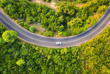 Wall Mural - aerial view of road with car in beautiful forest at sunset in summer. colorful landscape with asphal